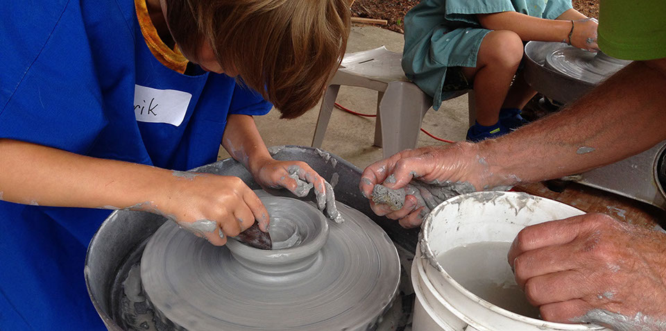 children making clay pots on a potter's wheel